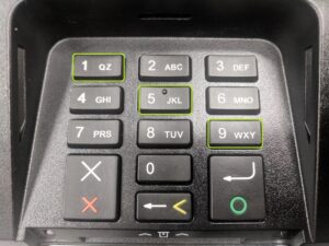 Verifone pinpad on a counter with reset instructions in the background